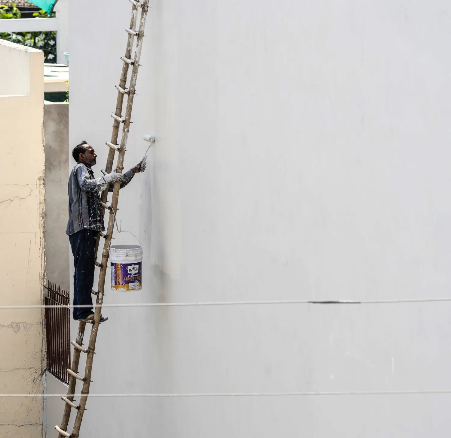 Peintre en façade appliquant une finition sur un mur extérieur